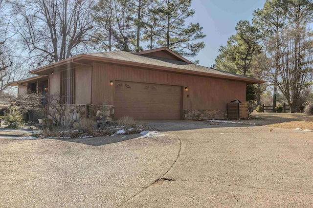 view of home's exterior with a garage, stone siding, and driveway