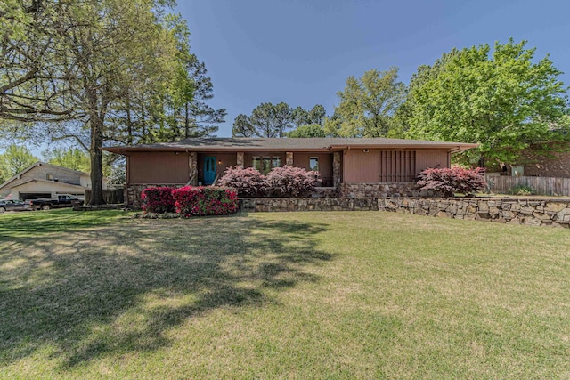 ranch-style home with a front yard, fence, and stone siding