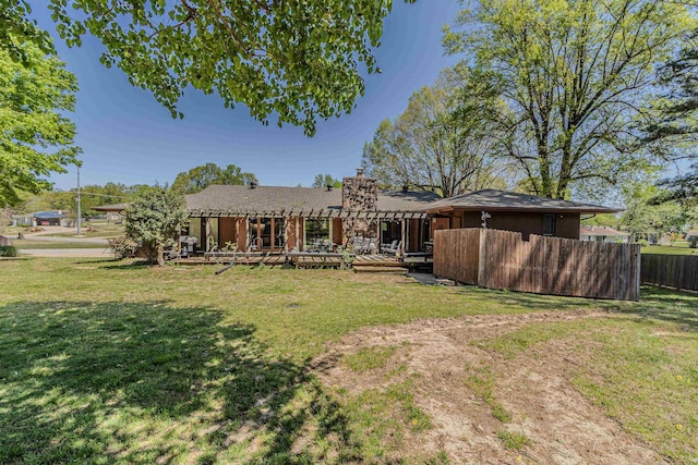 rear view of house featuring fence, a lawn, and a chimney