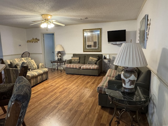 living room featuring visible vents, ceiling fan, a textured ceiling, and wood finished floors