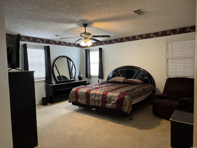 bedroom featuring light colored carpet, multiple windows, ceiling fan, and a textured ceiling