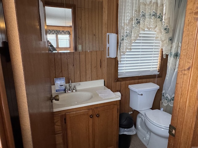 bathroom with toilet, wooden walls, and vanity