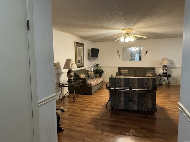 living room featuring a ceiling fan, a textured ceiling, and wood finished floors