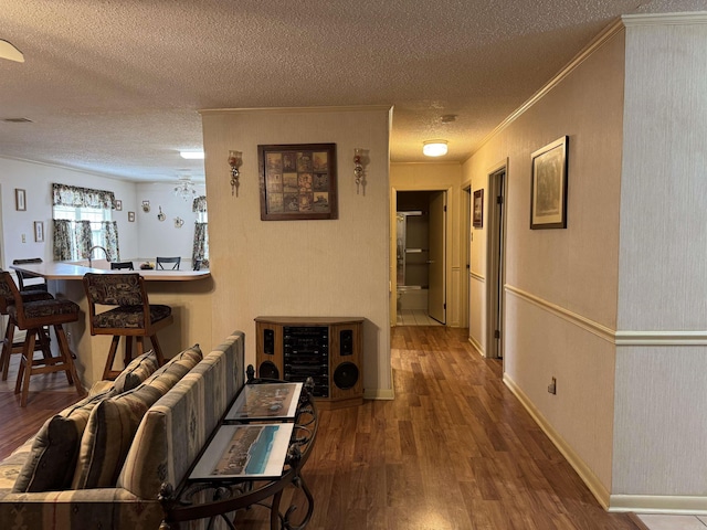 hallway with baseboards, visible vents, ornamental molding, wood finished floors, and a textured ceiling