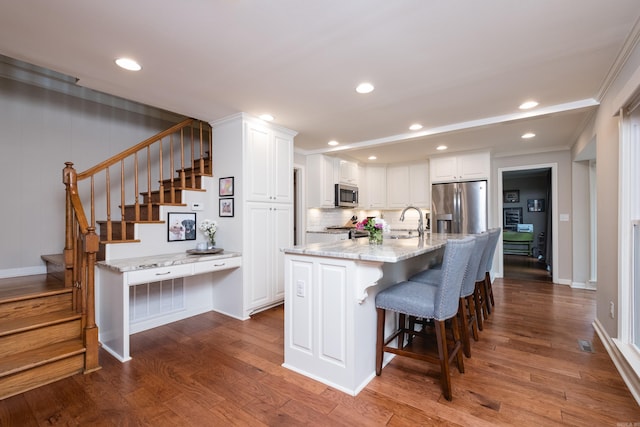 kitchen featuring light stone countertops, white cabinetry, stainless steel appliances, and dark wood finished floors