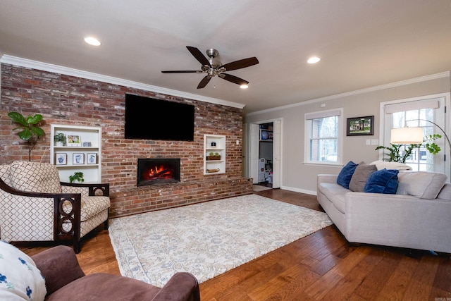 living room featuring brick wall, a fireplace, baseboards, ornamental molding, and wood-type flooring