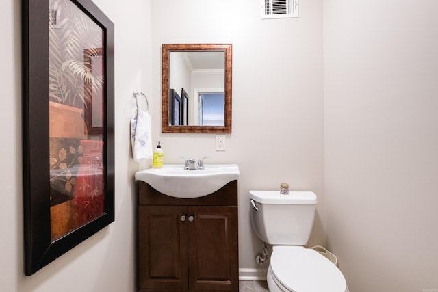 half bath with ornamental molding, visible vents, vanity, and toilet