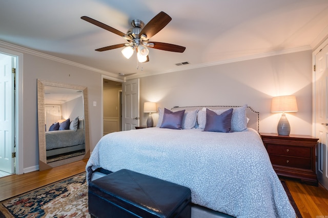 bedroom featuring ceiling fan, visible vents, crown molding, and wood finished floors