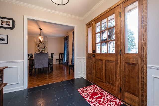 entryway featuring ornamental molding, dark tile patterned flooring, a wainscoted wall, and a decorative wall