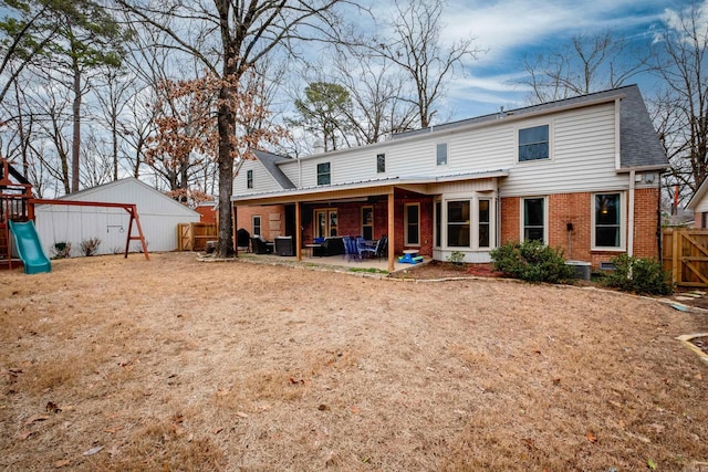 rear view of property with brick siding, a playground, fence, and a patio