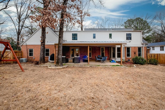 rear view of property featuring a patio, brick siding, central AC unit, and fence