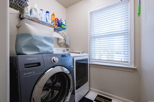 laundry area with laundry area, visible vents, washer and clothes dryer, and baseboards