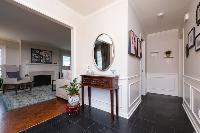 hallway with a wainscoted wall, ornamental molding, and a decorative wall