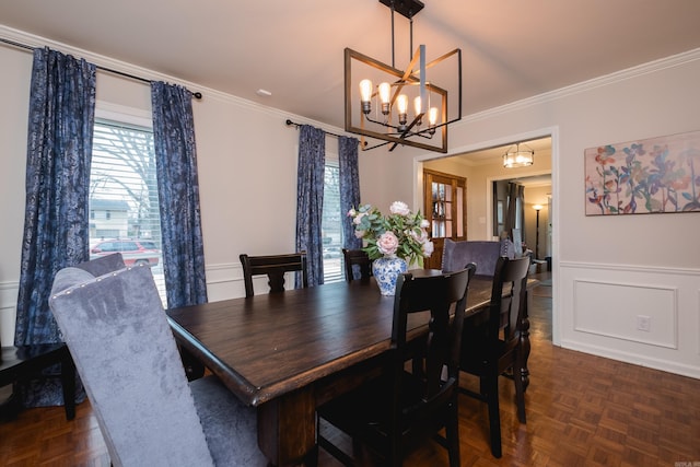 dining area with a chandelier, wainscoting, ornamental molding, and a decorative wall