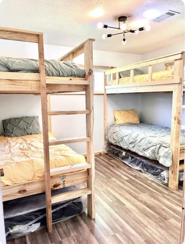 bedroom featuring visible vents, a textured ceiling, and wood finished floors