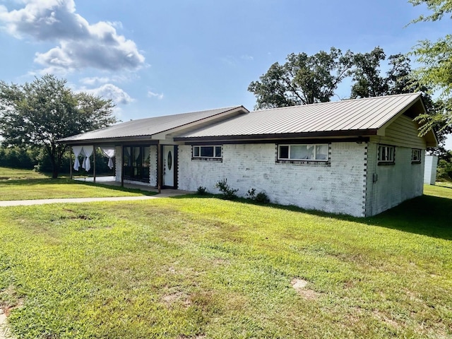 view of front of home featuring metal roof, a front lawn, and brick siding