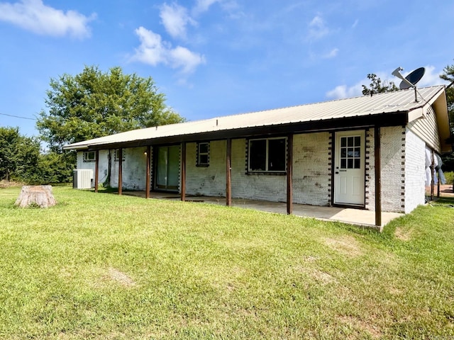 back of house with cooling unit, metal roof, and a lawn