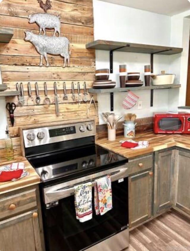 kitchen with custom range hood, stainless steel electric range, light wood-style floors, open shelves, and wooden counters