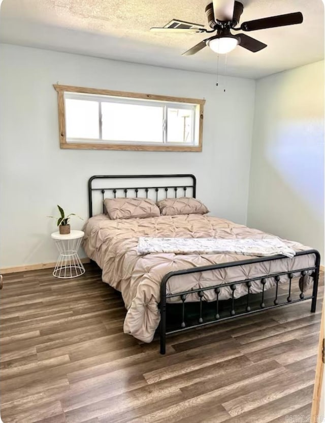 bedroom with a textured ceiling, wood finished floors, a ceiling fan, and baseboards