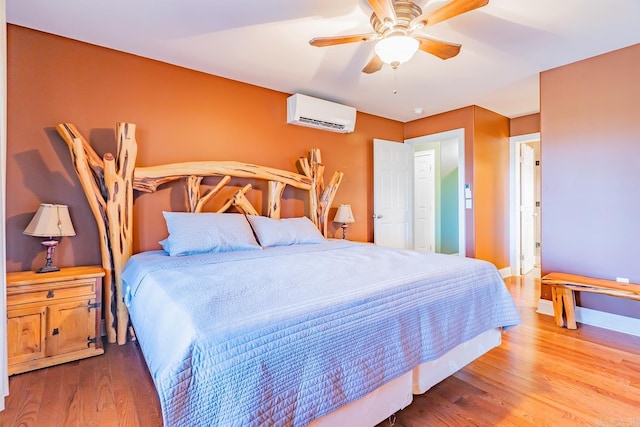 bedroom with a ceiling fan, baseboards, wood finished floors, and a wall mounted AC