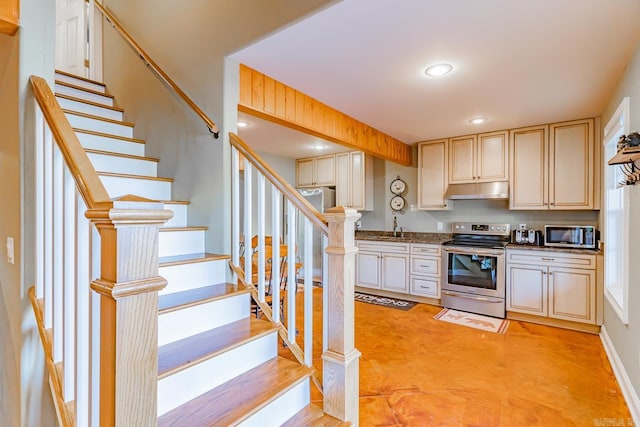 kitchen featuring recessed lighting, appliances with stainless steel finishes, a sink, dark stone countertops, and under cabinet range hood