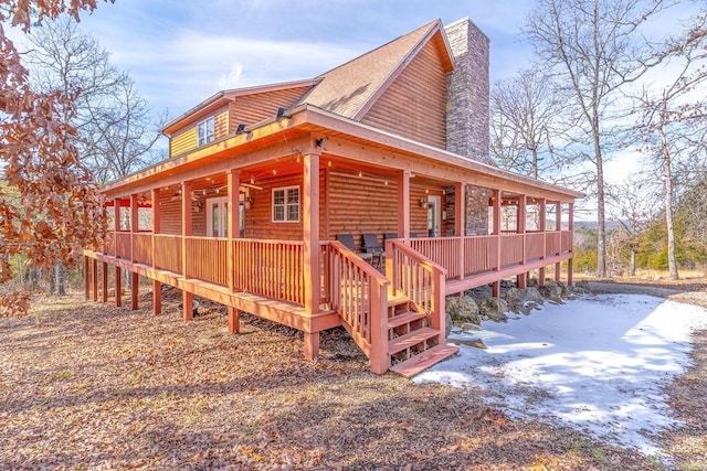 view of snowy exterior featuring a chimney and log veneer siding