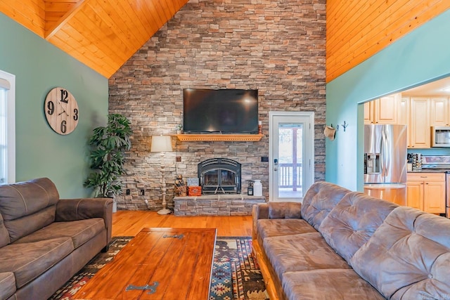 living room with high vaulted ceiling, a fireplace, and wood finished floors