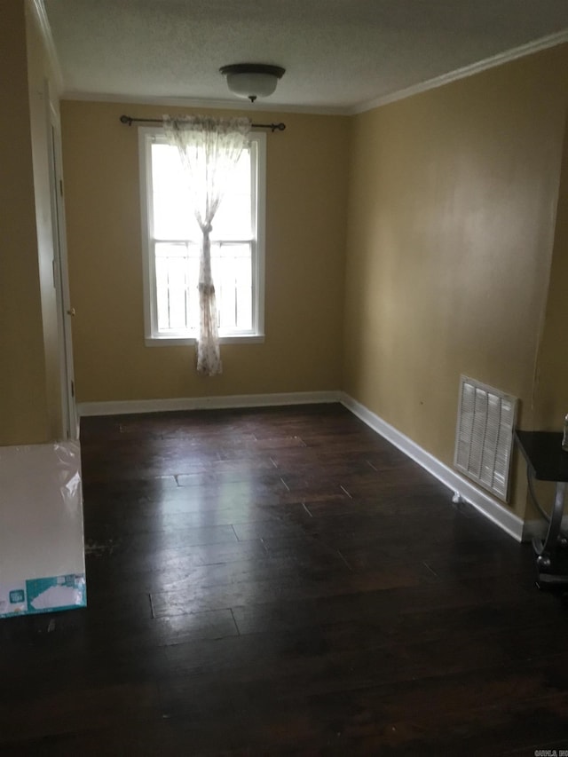 spare room with visible vents, dark wood-type flooring, baseboards, and crown molding