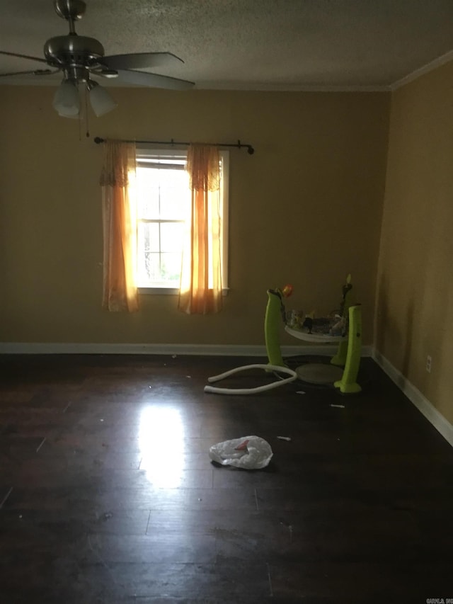 empty room featuring baseboards, ornamental molding, ceiling fan, and wood finished floors