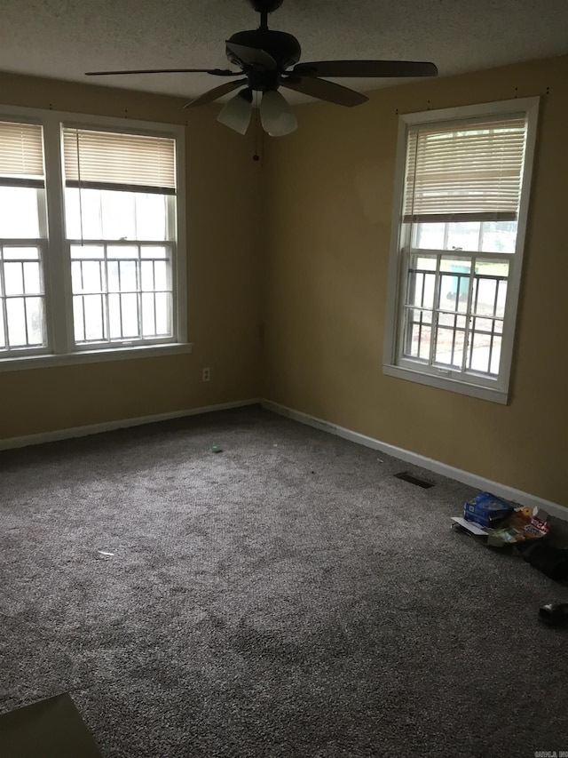 carpeted spare room featuring baseboards, plenty of natural light, and a ceiling fan