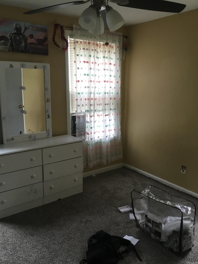 unfurnished bedroom with dark carpet, baseboards, and ceiling fan