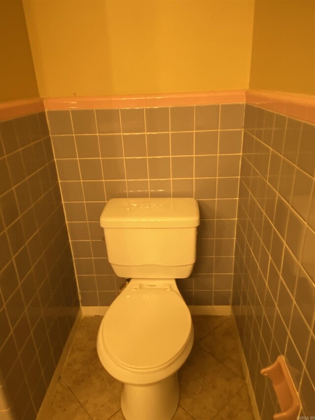 bathroom with wainscoting, tile walls, toilet, and tile patterned floors