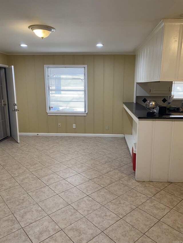 kitchen featuring dark countertops, a decorative wall, baseboards, and recessed lighting