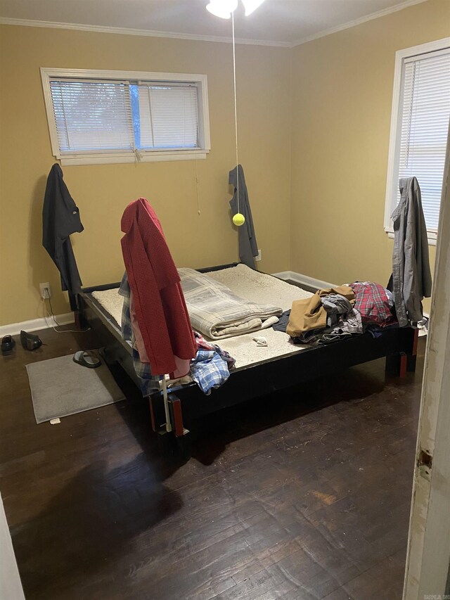 bedroom with baseboards, ornamental molding, and wood finished floors