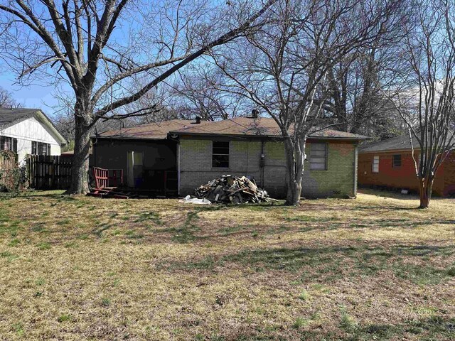 back of house featuring fence, a lawn, and brick siding