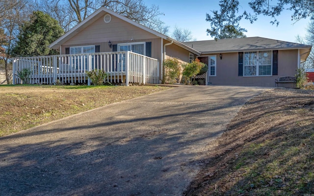 ranch-style house with a wooden deck and a front yard