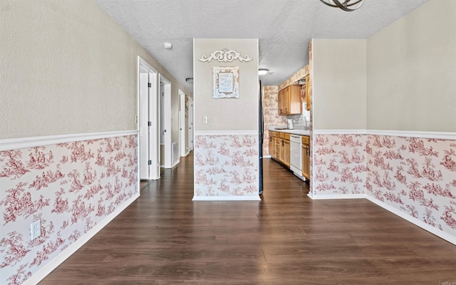 interior space featuring dark wood-style floors, a textured ceiling, baseboards, and wallpapered walls