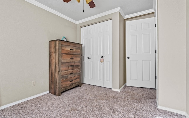 unfurnished bedroom featuring light carpet, a ceiling fan, baseboards, a closet, and crown molding