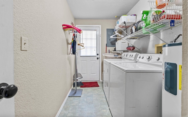 clothes washing area with a textured wall, electric water heater, laundry area, baseboards, and washer and clothes dryer