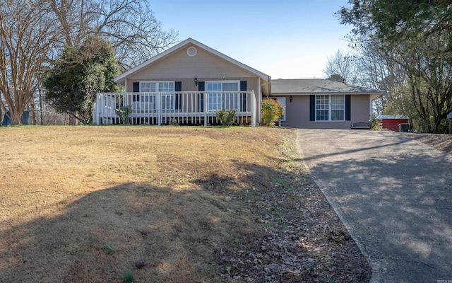 ranch-style home with driveway, a deck, and a front yard