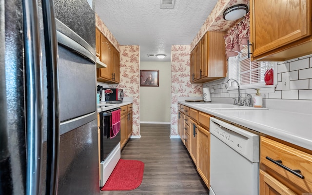 kitchen with brown cabinets, light countertops, a sink, a textured ceiling, and white appliances