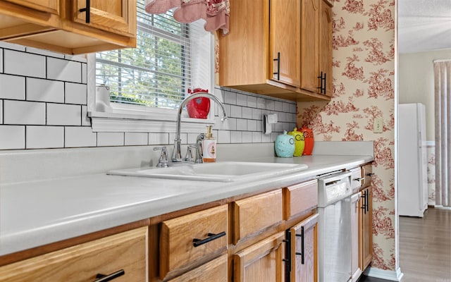 kitchen featuring white appliances, light countertops, a sink, and wallpapered walls