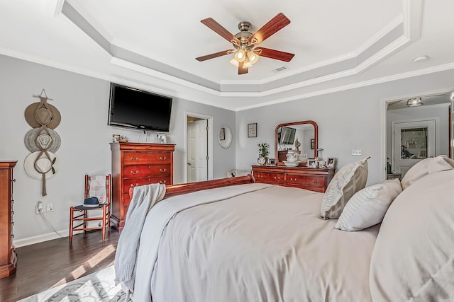 bedroom featuring visible vents, a tray ceiling, dark wood-style flooring, and ornamental molding