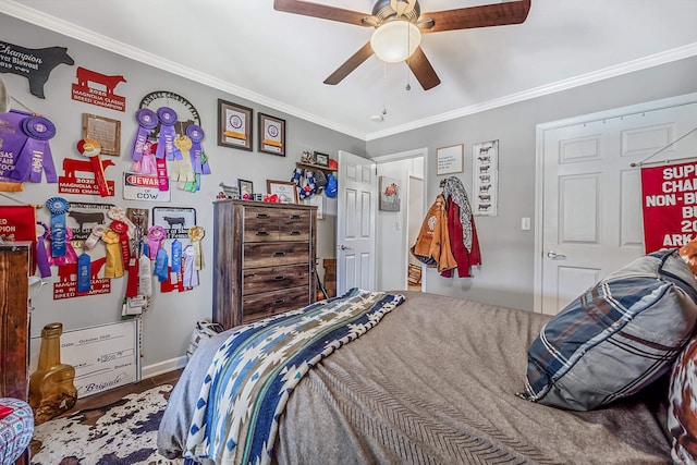 bedroom featuring a ceiling fan, crown molding, baseboards, and wood finished floors