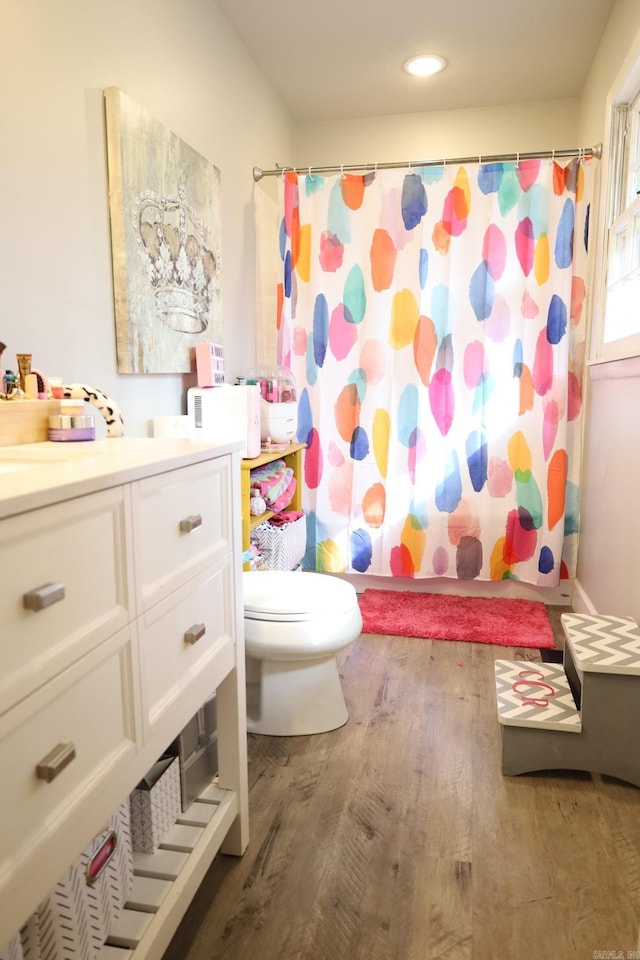 bathroom featuring toilet, recessed lighting, wood finished floors, vanity, and shower / bath combination with curtain