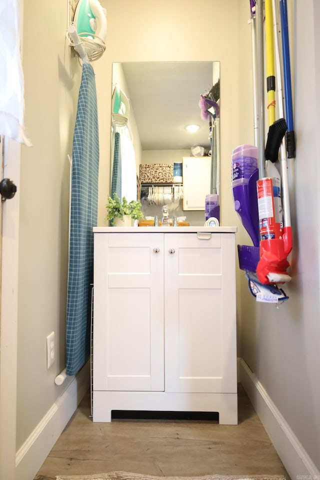 bathroom featuring vanity, baseboards, and wood finished floors