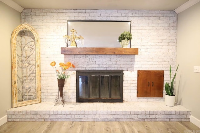 room details with ornamental molding, a brick fireplace, wood finished floors, and baseboards