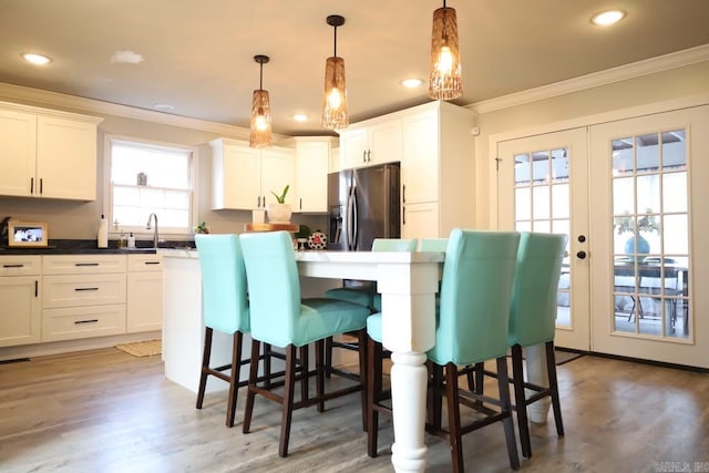 kitchen with white cabinetry, french doors, dark countertops, stainless steel fridge, and decorative light fixtures