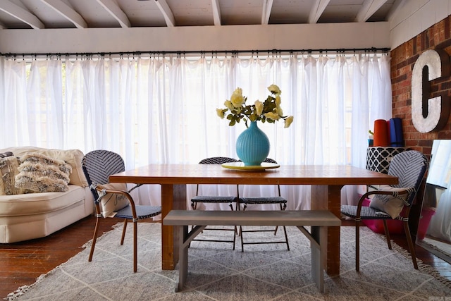 dining area with beam ceiling and wood finished floors