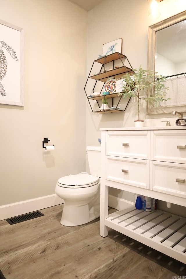 full bathroom featuring baseboards, visible vents, toilet, wood finished floors, and a sink